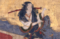 A kabuki performer with a sword performs against a gold background